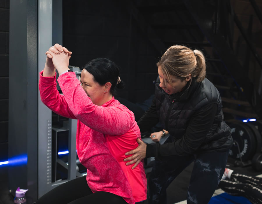 Personal trainer Leannda helping class member with exercise technique