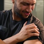 Bodybuilder with shoulder pain in the gym.